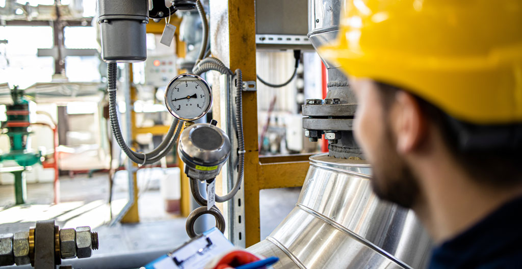 Gros plan sur un manomètre indiquant la pression sur un circuit de test, avec arrière-plan industriel flouté